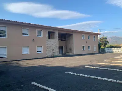 an empty parking lot in front of a building at Appartement avec piscine à 50 m de la plage in Propriano