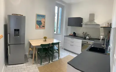 a kitchen with a small table and a refrigerator at Superbe appartement centre ville Ajaccio in Ajaccio