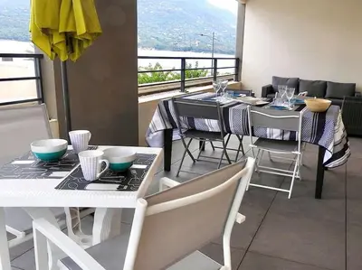 a dining room with a table and chairs and a balcony at Splendide T3 neuf au bord de la plage in Propriano