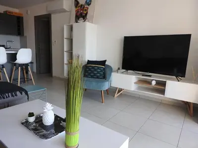 a living room with a flat screen tv and a table at Splendide T3 neuf au bord de la plage in Propriano