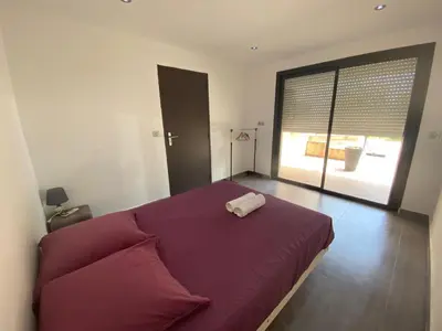 a bedroom with a purple bed with a large window at Bas de villa - Canella in Sari Solenzara
