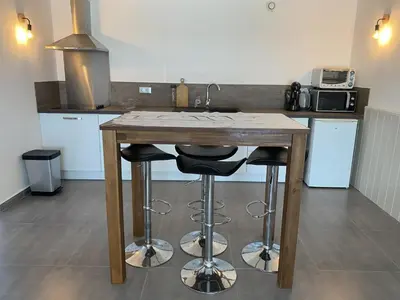 a kitchen with a wooden table with two stools at Bas de villa - Canella in Sari Solenzara