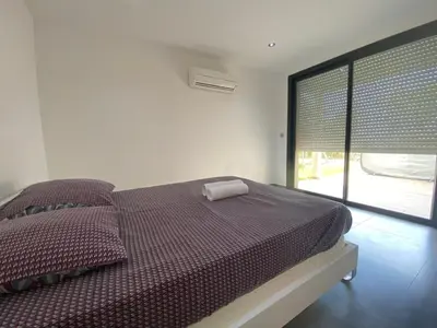 a bedroom with a bed and a large window at Bas de villa - Canella in Sari Solenzara