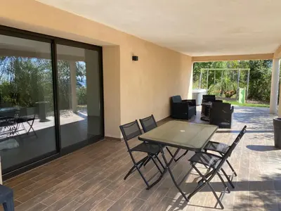 a patio with a table and chairs and glass doors at Bas de villa - Canella in Sari Solenzara