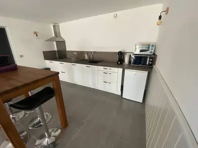 a kitchen with white cabinets and a table and a microwave at Bas de villa - Canella in Sari Solenzara
