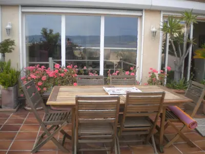 a wooden table and chairs on a patio with flowers at Chambre hôtes Wagram in Ajaccio