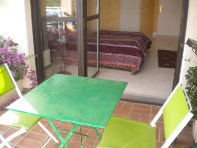 a green table and two chairs in a room with a bed at Chambre hôtes Wagram in Ajaccio