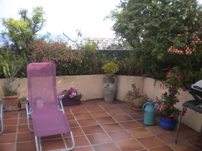a pink chair sitting on a patio with plants at Chambre hôtes Wagram in Ajaccio
