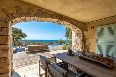 an archway in a patio with a table and a couch at Villa Sud Corse 6ch piscine 27m, accès mer in Pianottoli-Caldarello