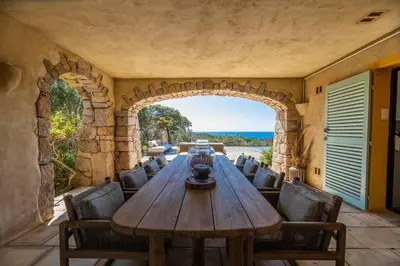 an outdoor dining room with a wooden table and chairs at Villa Sud Corse 6ch piscine 27m, accès mer in Pianottoli-Caldarello
