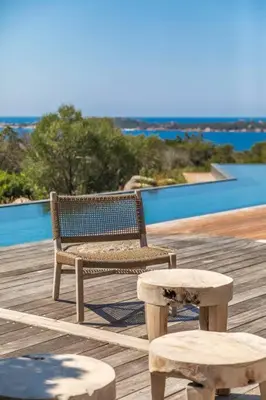 a wooden bench and two stools on a deck at Villa Sud Corse 6ch piscine 27m, accès mer in Pianottoli-Caldarello