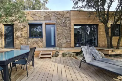 a patio with a table and chairs and a stone wall at Bergerie entièrement rénovée in Viggianello