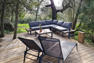 a patio with a couch and chairs on a wooden deck at Bergerie entièrement rénovée in Viggianello