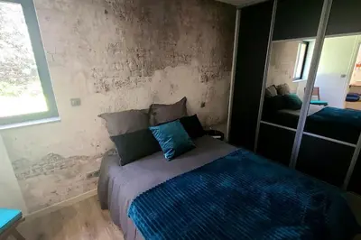 a bedroom with a bed with a blue comforter and a mirror at Bergerie entièrement rénovée in Viggianello