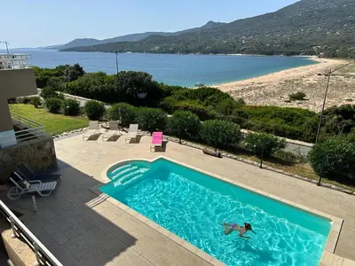a person swimming in a swimming pool next to a beach at Grand appartement T4, piscine, vue exceptionnelle à 50 m de la plage in Propriano