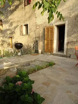 a stone building with a door and a grill at Authentique maison de village de Gavignano in Gavignano