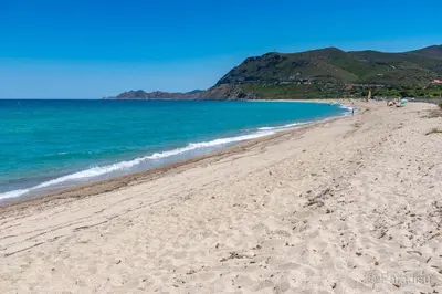 a sandy beach with the ocean and mountains in the background at Authentique maison de village de Gavignano in Gavignano