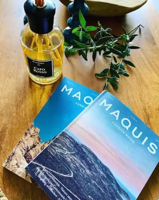 a magazine and a bottle of perfume on a table at Vignarella meublé de tourisme classé 5 étoiles avec terrasse in Piana