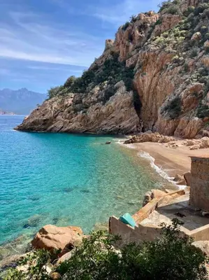 a beach with blue water and a rocky mountain at Vignarella meublé de tourisme classé 5 étoiles avec terrasse in Piana