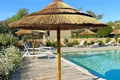 a large straw umbrella next to a swimming pool at Duplex Marina Di Cala Rossa in Lecci