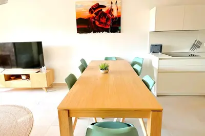 a dining room with a wooden table and green chairs at Duplex Marina Di Cala Rossa in Lecci
