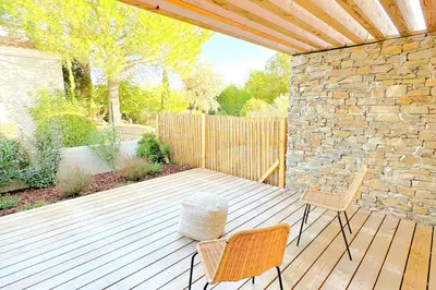 a wooden deck with two chairs and a stone wall at Duplex Marina Di Cala Rossa in Lecci