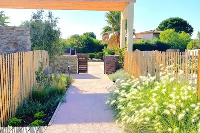 a garden with a wooden fence and a sidewalk at Duplex Marina Di Cala Rossa in Lecci