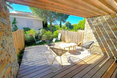 a patio with a table and chairs on a wooden deck at Duplex Marina Di Cala Rossa in Lecci