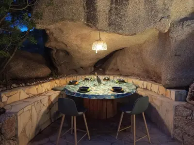 a table in a cave with chairs and a light fixture at Bergerie U Caseddu in Pianottoli-Caldarello