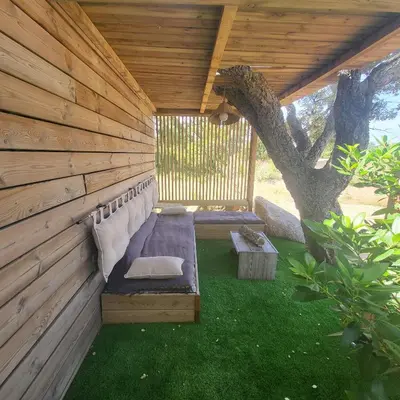 a wooden pergola with a bench and a tree at La RoseDan in Pianottoli-Caldarello