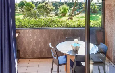 a table and chairs on a balcony with a window at Lovely Apartment In Moriani Plage in Moriani Plage