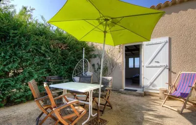 a table and chairs with a green umbrella on a patio at Gîtes et Astrotourisme en Corse in Erbajolo