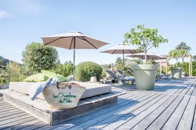 a couple of beds on a wooden deck with umbrellas at Hotel Les Chambres de Mila Bonifacio in Bonifacio