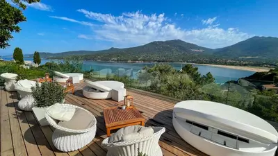 a deck with white chairs and a view of the water at A'mare Corsica I Seaside Small Resort in Propriano
