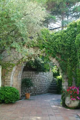 an archway in a stone wall with flowers and plants at A'mare Corsica I Seaside Small Resort in Propriano