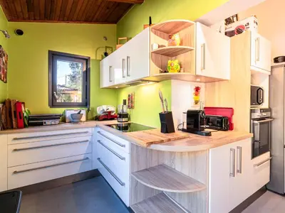 a kitchen with white cabinets and green walls at Villa Villa Romana by Interhome in Porto-Vecchio