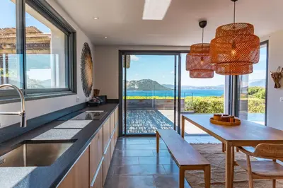 a kitchen with a dining table and a view of the ocean at Villa Cala Rossa Di Lecci in Lecci