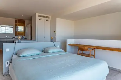 a bedroom with a blue bed and a kitchen at Villa Cala Rossa Di Lecci in Lecci
