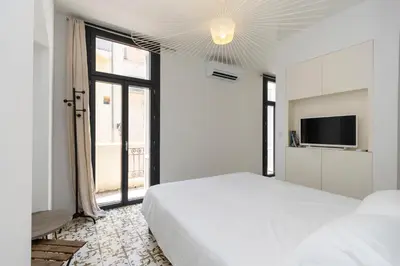 a white bedroom with a bed and a tv at Les Appartements du Roi de Rome - Hypercentre Ajaccio in Ajaccio