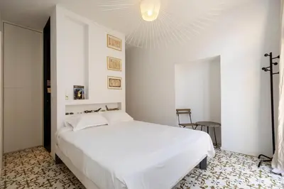 a bedroom with a white bed and a chandelier at Les Appartements du Roi de Rome - Hypercentre Ajaccio in Ajaccio