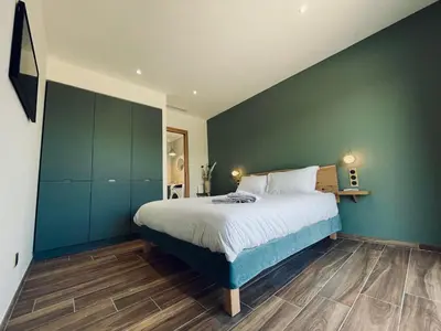 a bedroom with a bed and a green wall at Domaine Aria di Terra***** in Figari