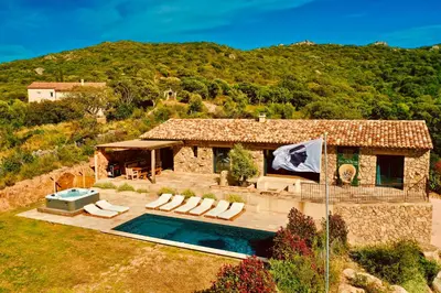 a house with a swimming pool in front of a mountain at Domaine Aria di Terra***** in Figari