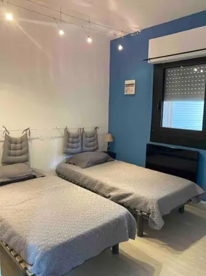 two beds in a room with a blue wall at Maison SAINTE LUCIE DE PORTO-VECCHIO in Sainte-Lucie de Porto-Vecchio