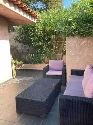 a patio with two wicker chairs and two tables at Maison SAINTE LUCIE DE PORTO-VECCHIO in Sainte-Lucie de Porto-Vecchio