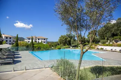 a large swimming pool with chairs and a tree at Domaine d'Arca - Flaubert 22 - 3 pièces - étage 2 - Porto-Vecchio in Porto-Vecchio