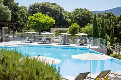 a large swimming pool with chairs and umbrellas at Domaine d'Arca - Flaubert 22 - 3 pièces - étage 2 - Porto-Vecchio in Porto-Vecchio