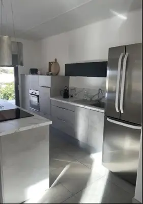 a kitchen with white cabinets and a stainless steel refrigerator at MONTE LEONE in Bonifacio