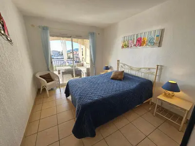 a bedroom with a bed with a blue comforter at Palmeraie 130- vue mer et village- plage et commerces à pieds in Sari Solenzara