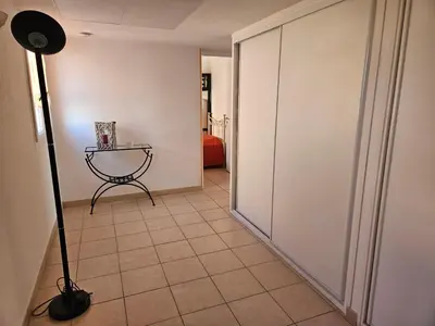 a hallway with a table and a floor lamp at Palmeraie 130- vue mer et village- plage et commerces à pieds in Sari Solenzara