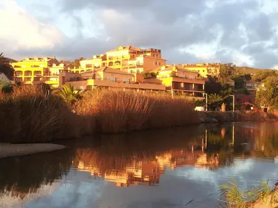 a group of buildings sitting next to a body of water at Palmeraie 130- vue mer et village- plage et commerces à pieds in Sari Solenzara